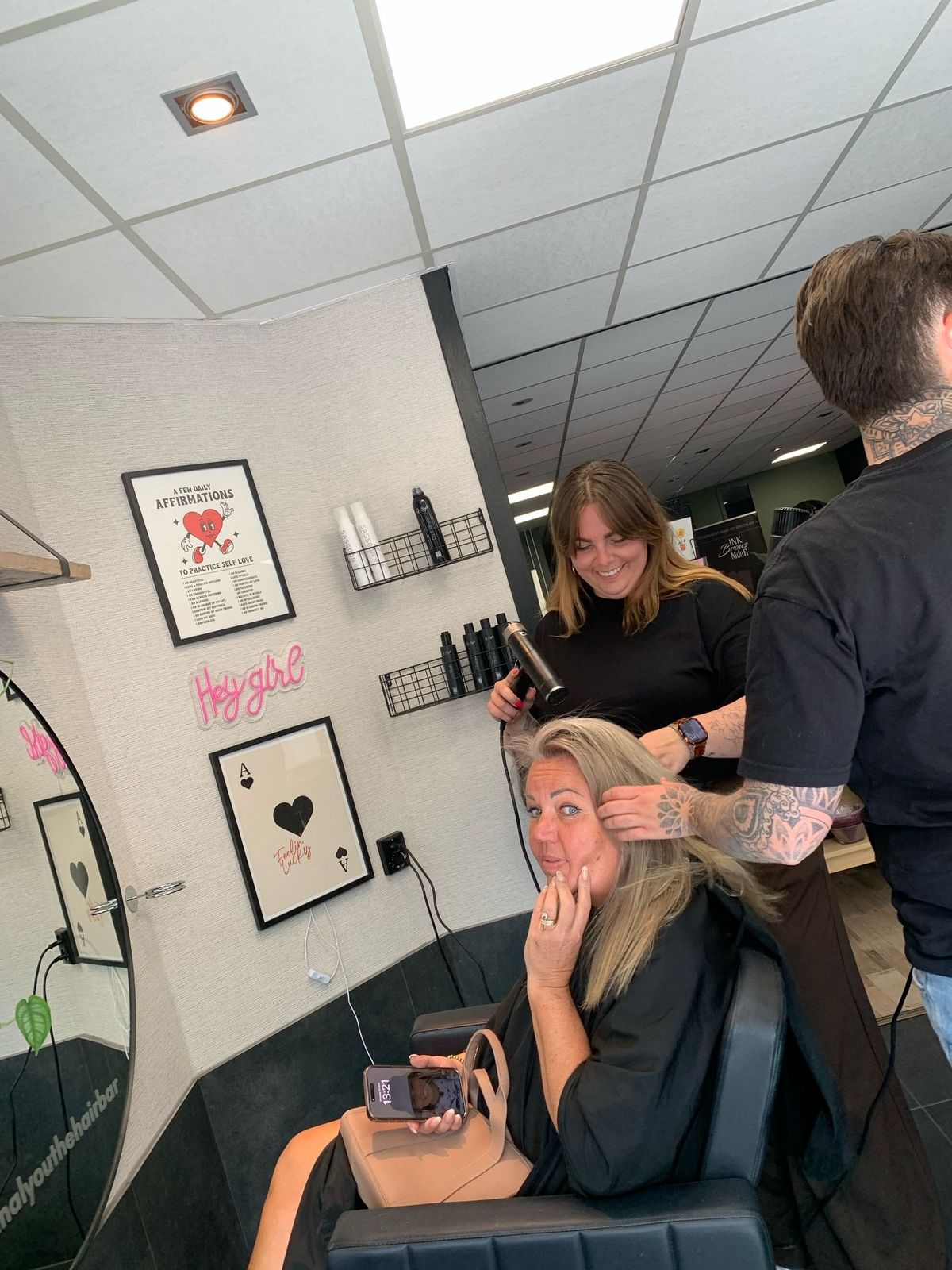 Aan het werk in de salon: föhnen en knippen, met een lachende klant in de stoel